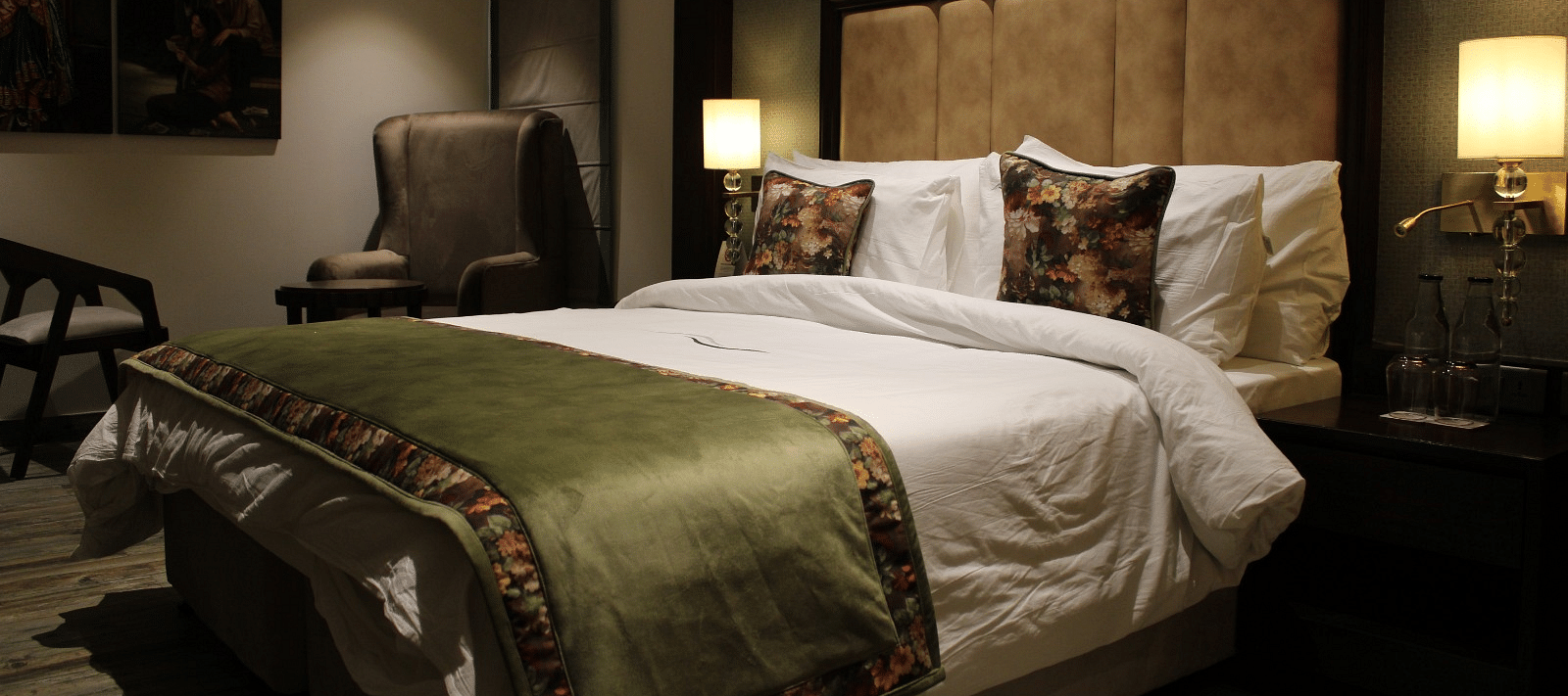 Side view of the bedroom with multiple pillows arranged on the bed and a huge chair next to it at BluSalzz Residence, Amritsar